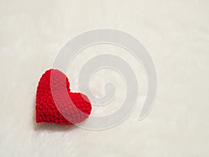 Handmade red yarn heart on white wool. the red heart on the left corner of picture and background copy space for text.