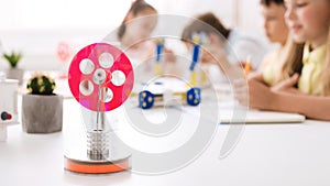 Handmade robotic wheel on desk with schoolchildren on background