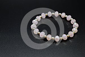 Handmade rose quartz bracelet with silver beads on a dark background