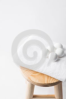 Handmade salt bath bombs in balls shape from organic vegan natural ingredients on white towel on wooden stool in bathroom. Spa