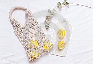 Handmade shopping macrame bag with lemon on the white cotton background