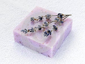 Handmade soap bar with dry aromatic lavender flowers. Purple  soap on a white terry cotton towel. Natural toiletries and hygiene