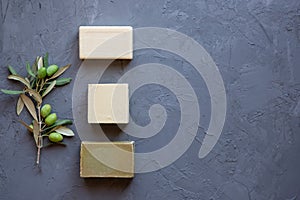 Handmade soap bars and olive branch on grey background, beauty treatment ,top view copy space