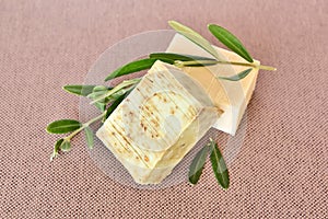 Handmade soap bars and olive branches on fabric background