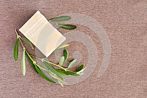 Handmade soap bars and olive branches on gunny background.