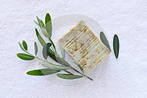 Handmade soap bars and olive branches on a white towel.