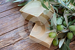 Handmade soap bars and olive branches on wooden background, beauty treatment ,top view copy space