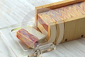 Handmade soap being cut using a wire cutter on marble backdrop