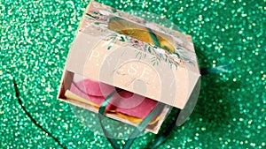 Handmade soap in festive packaging on a shiny green background.