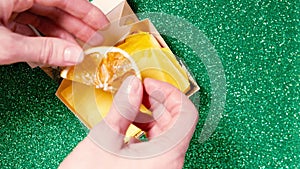 Handmade soap in festive packaging on a shiny green background.