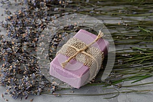 Handmade soap with natural ingredients and dry lavender flowers on a gray concrete background. Close-up