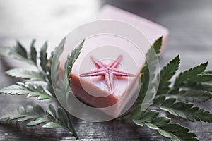 Handmade soap, starfish and green leaves on a wooden background