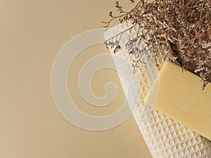 Handmade soap, towels and dried flowers on a beige background. Space for text