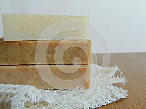 Handmade spa bath soap on white handmade linen waffle texture wash cloth, towel, wooden background.
