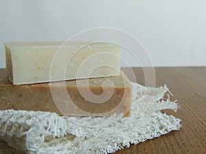 Handmade spa bath soap on white handmade linen waffle texture wash cloth, towel, wooden background.