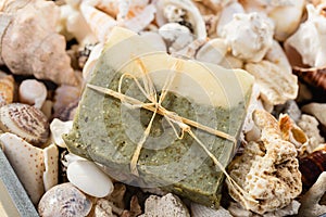 Handmade spa olive oils and dried herbs soap on seashells background