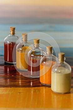 Handmade spicy sauces in glass bottles with cork on a colored wooden base photo