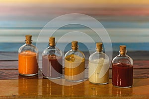Handmade spicy sauces in glass bottles with cork on a colored wooden base - Salsas picantes hechas artesanalmente en botellas de photo
