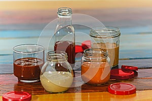 Handmade spicy sauces in glass jars on a colored wooden base photo