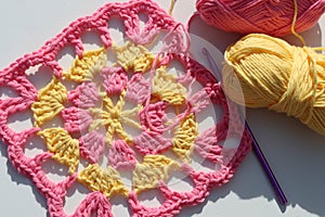 Handmade square motive crocheted of pink and yellow cotton yarn
