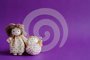 Handmade textile dolls on purple background.