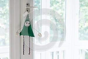 Handmade toy green creature on window