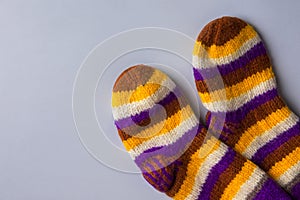 Handmade warm knitted woolen multicolored striped socks on gray background. Winter autumn eco fashion clothing