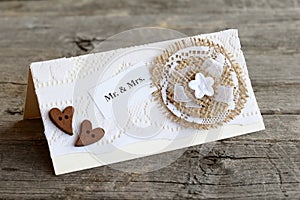 Handmade wedding invitation card decorated with lace and burlap flower and wooden hearts. Closeup