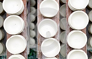 Handmade white clay pots dry on wooden planks. Top view. Workshop, manufactory