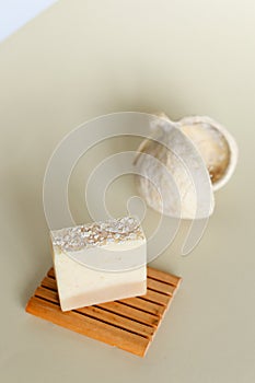 Handmade white herbal soap with olive oil on wooden stand.