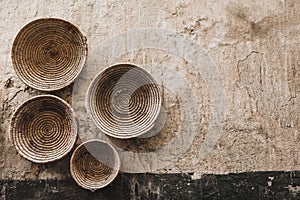 Handmade wicker round baskets hanging on textured wall in Marrakech medina souk