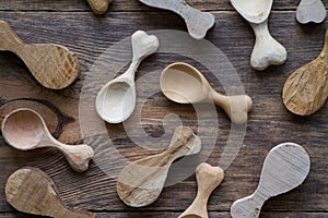 Handmade wooden utensils, top view lot of billets and spoons on wooden table, selective focus