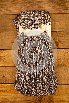 Handmade wool knitted winter grey and white hat and scarf on wood background