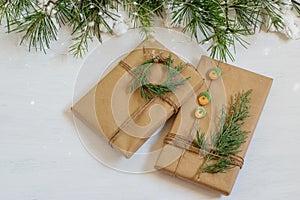 Handmade wrapped in craft paper gifts on the festive Christmas table. Christmas tree branches, nice snow bokeh. Mock up photo,