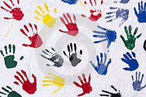 Handprints in yellow, blue, red, green, black on a white wall, background