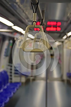 A handrail in focus inside a train designed to be grasped by standing passengers to provide support