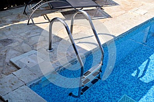 Handrail on pool. Swimming pool with stair at tropical resort. Pool handrails view. Water swimming pool with sunny reflection.
