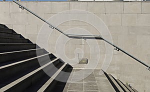 Handrails on the side of gray granite tiled wall along the stone staircase.