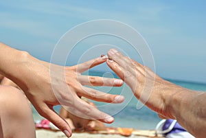 Hands of 2 people of the European race reach out to each other in front of the sea, 2 ladybugs sit on their fingers