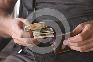 The hands of an adult man who has taken small bills out of his wallet. Close-up