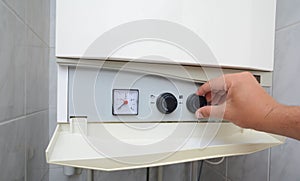 Hands adult men set the temperature of the water in the gas boiler.