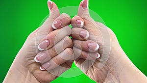 hands of adult woman close-up in frame on green background chroma key examining french manicure holding hands in front