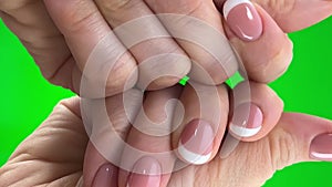 Hands of adult woman close-up in frame on green background chroma key examining french manicure holding hands in front