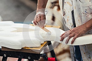 Hands of an adult woman shaping a piece of polystyrene using cream photo