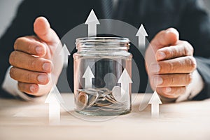 Hands of adults holding money jar with house icon