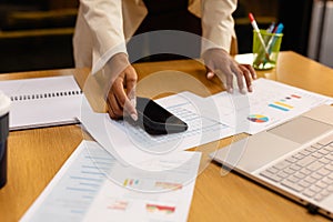 Hands of african american casual businesswoman using smartphone and laptop in office