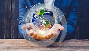 hands of a african american child holding crystal glowing globe planet earth at a sunny green meadow background copyspace taking