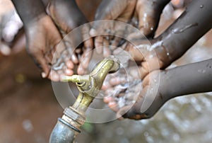 Hands of African Children Cupped under Tap Drinking Water Malnutrition. Hands of African black boys and girls with water pouring