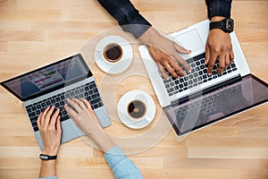 Hands of african man and caucasian woman typing on laptops