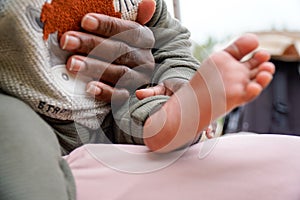 Hands of an African mother holding her baby in the foreground